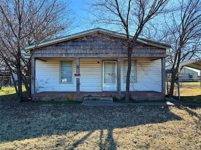 bungalow featuring covered porch and a front yard