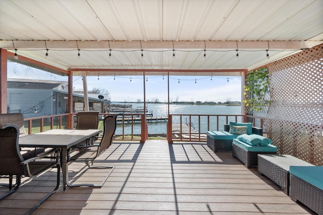 deck with outdoor dining area and a water view