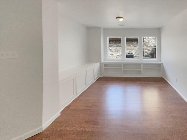 unfurnished room featuring visible vents, a decorative wall, and wood finished floors