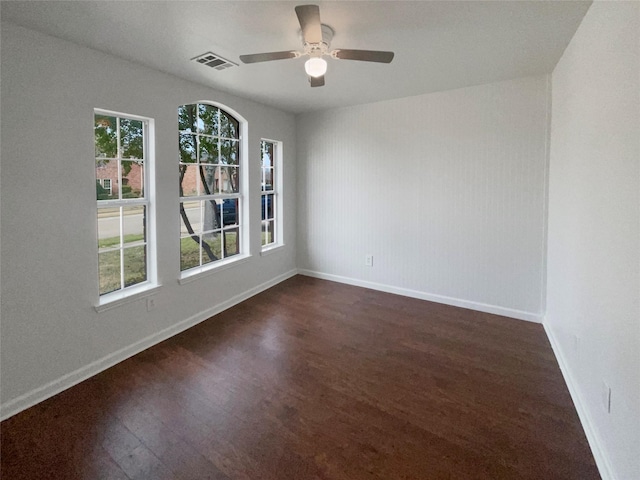 empty room with visible vents, baseboards, dark wood-type flooring, and ceiling fan