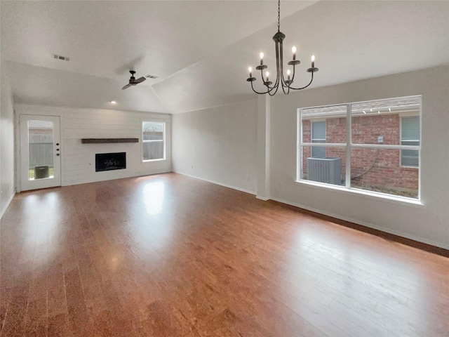 unfurnished living room with visible vents, lofted ceiling, ceiling fan with notable chandelier, a fireplace, and wood finished floors