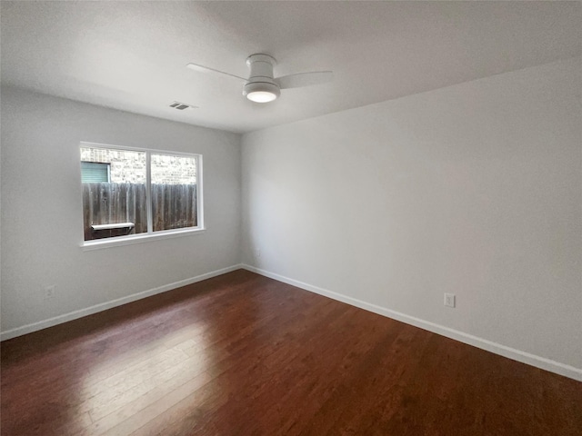 spare room with visible vents, ceiling fan, baseboards, and dark wood-style flooring