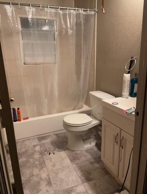 full bath featuring vanity, toilet, shower / tub combo with curtain, and a textured wall