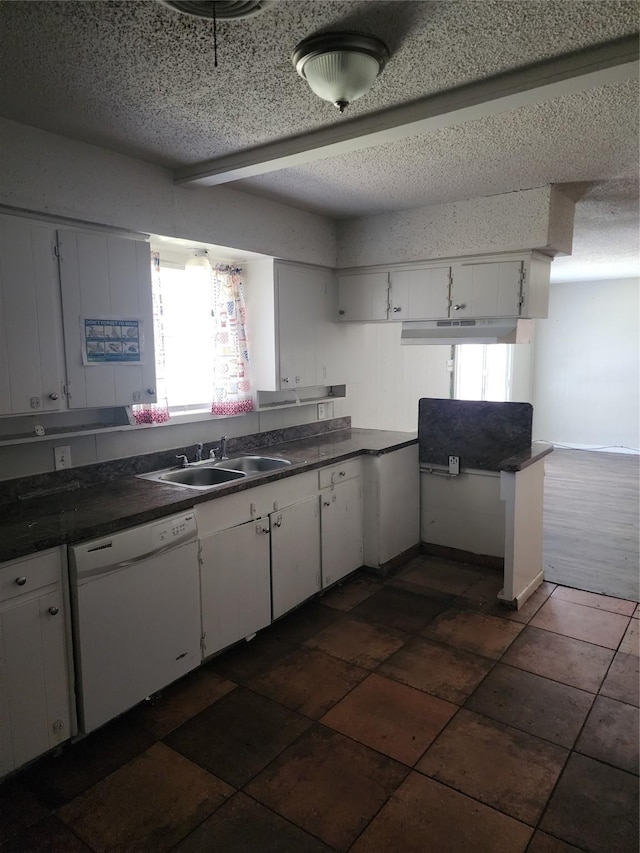 kitchen featuring white dishwasher, a sink, white cabinets, under cabinet range hood, and dark countertops