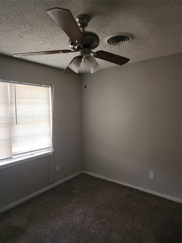 spare room featuring a ceiling fan, baseboards, visible vents, a textured ceiling, and dark colored carpet