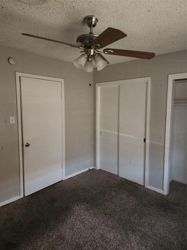 unfurnished bedroom with carpet flooring, a ceiling fan, two closets, and a textured ceiling