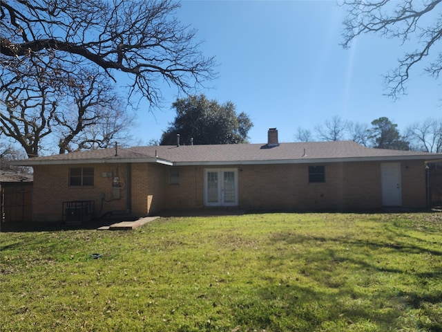 rear view of property featuring french doors, a yard, cooling unit, brick siding, and a chimney