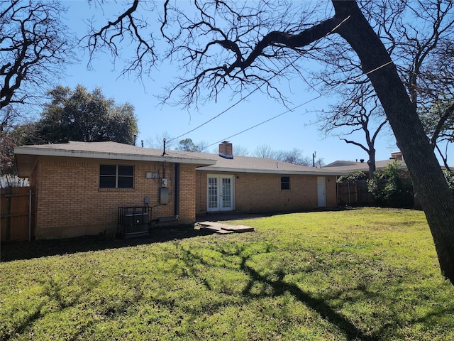 back of house featuring french doors, brick siding, a chimney, and fence