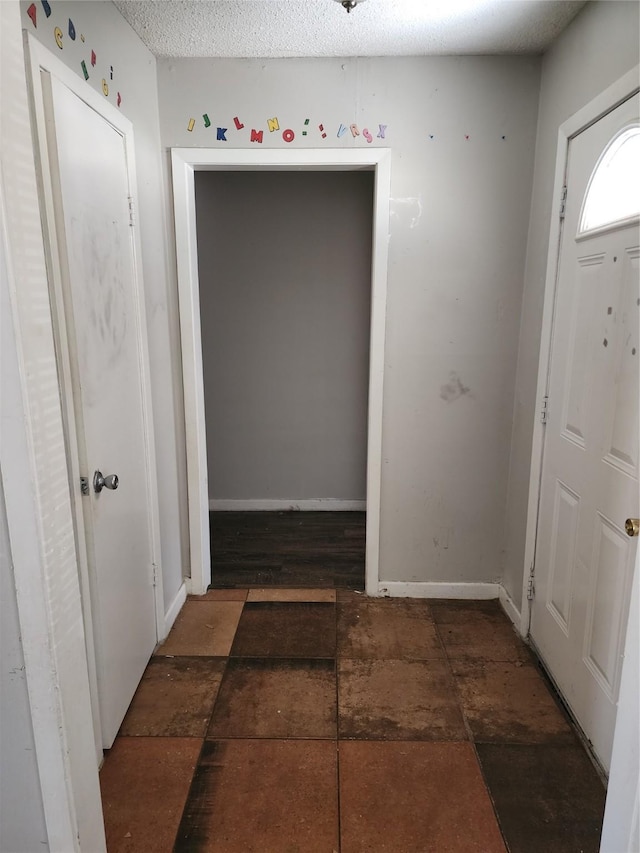 entrance foyer featuring baseboards, a textured ceiling, and stone finish floor