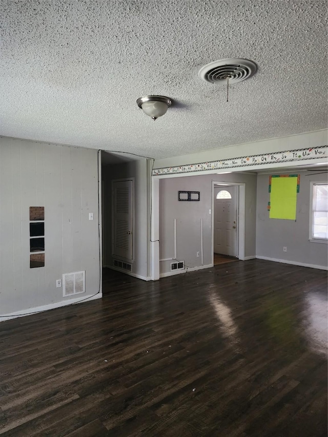 unfurnished living room with visible vents, a textured ceiling, and wood finished floors