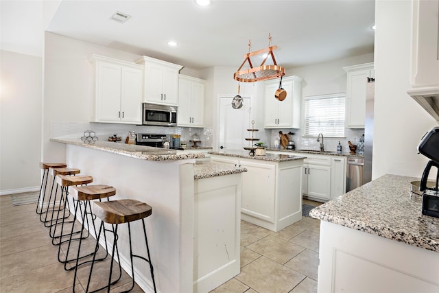 156 Palisade Dr, Gun Barrel City, TX 75156 - kitchen featuring visible vents, a kitchen bar, appliances with stainless steel finishes, white cabinets, and a sink