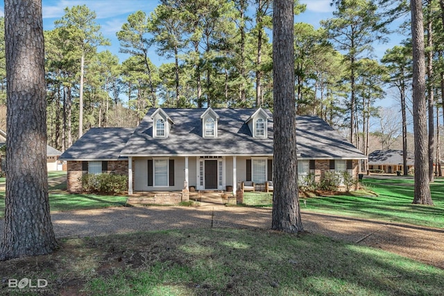 cape cod-style house featuring brick siding, covered porch, and a front lawn