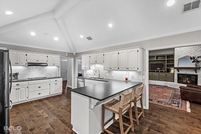 kitchen with visible vents, a sink, dark countertops, stainless steel appliances, and vaulted ceiling with beams