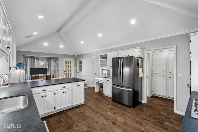 kitchen with dark countertops, vaulted ceiling with beams, freestanding refrigerator, white cabinets, and a sink