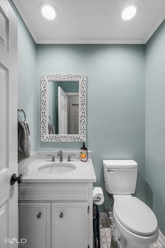 half bathroom with vanity, crown molding, toilet, and tile patterned floors