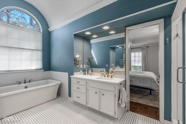 full bathroom with double vanity, a soaking tub, a sink, crown molding, and connected bathroom