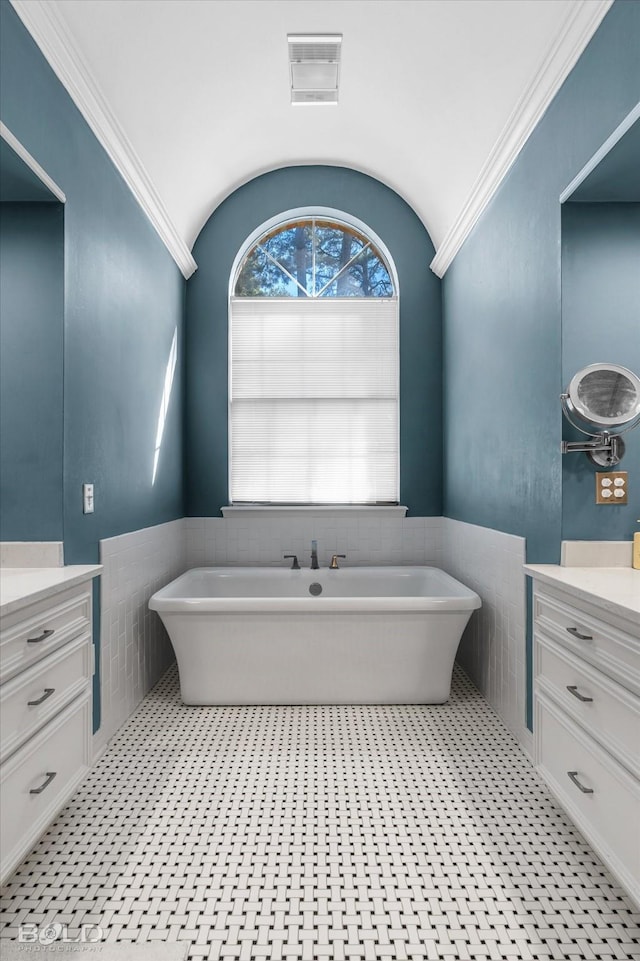 bathroom with visible vents, wainscoting, a freestanding bath, and vanity