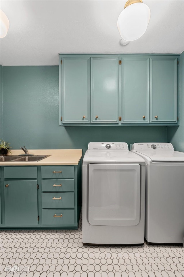 laundry area featuring washing machine and clothes dryer, cabinet space, and a sink