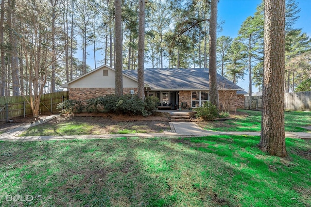 view of front of property featuring brick siding, covered porch, a front yard, and fence