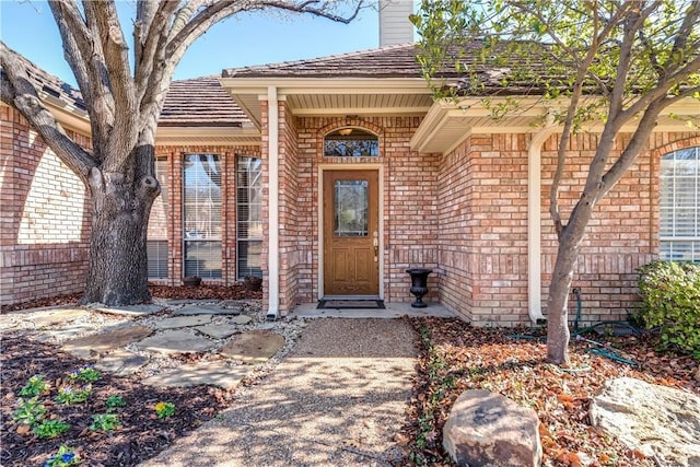 entrance to property featuring brick siding and a chimney