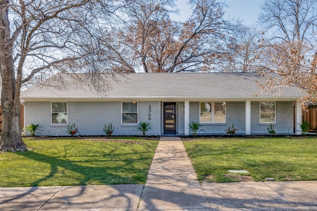 view of front of property featuring brick siding, a front lawn, and roof with shingles