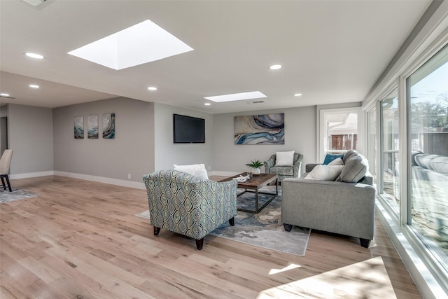 living area with recessed lighting, light wood-type flooring, baseboards, and a skylight