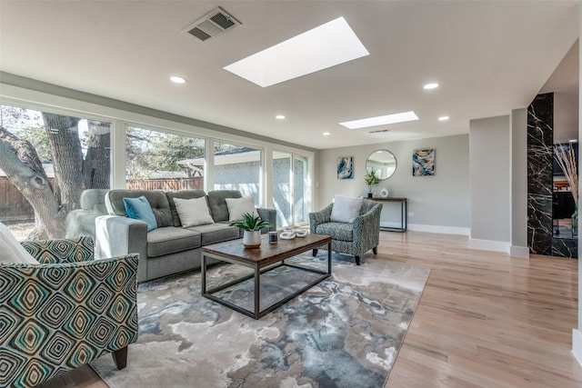 living room with visible vents, baseboards, recessed lighting, a skylight, and light wood-style floors