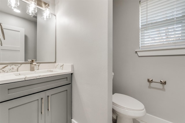 bathroom featuring vanity, toilet, and baseboards