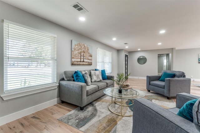 living area with light wood-type flooring, visible vents, and baseboards