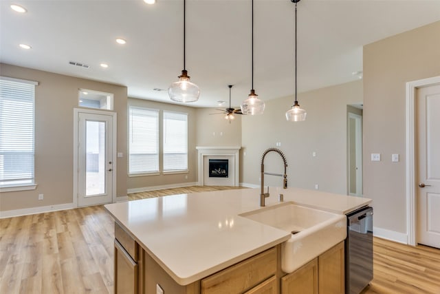 kitchen featuring light wood finished floors, visible vents, dishwasher, a fireplace, and a sink