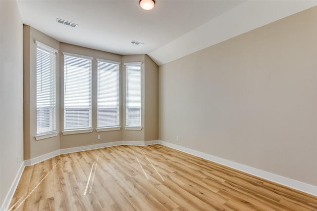 spare room with visible vents, light wood-style flooring, and baseboards