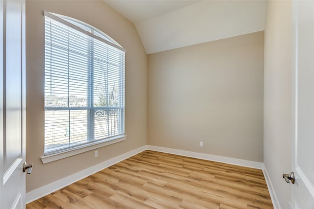 spare room with baseboards, light wood-style floors, and lofted ceiling