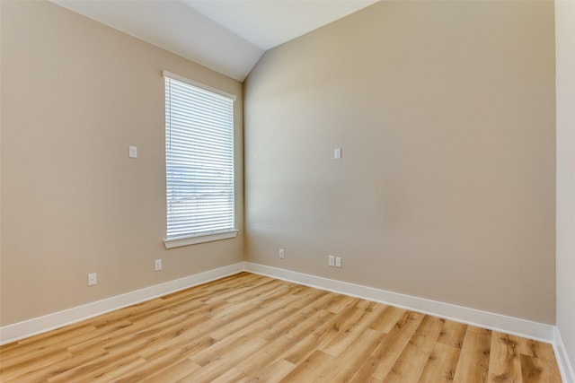 spare room with lofted ceiling, light wood-style floors, and baseboards