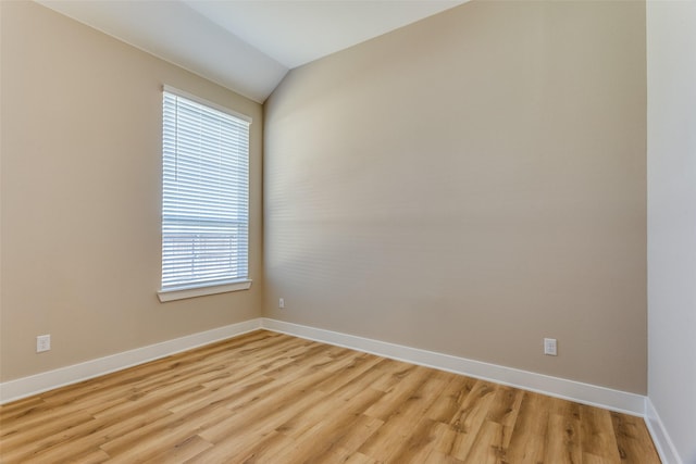 spare room with light wood finished floors, lofted ceiling, and baseboards