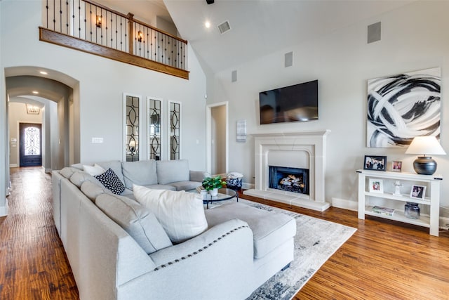 living area featuring visible vents, wood finished floors, arched walkways, and a fireplace with raised hearth