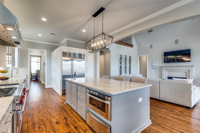 kitchen with a warming drawer, visible vents, appliances with stainless steel finishes, crown molding, and extractor fan