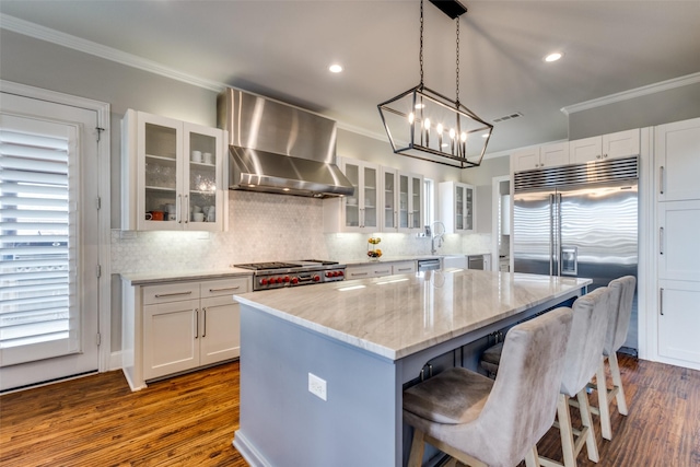 kitchen featuring visible vents, appliances with stainless steel finishes, ornamental molding, and wall chimney range hood