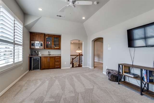 kitchen with visible vents, lofted ceiling, arched walkways, wine cooler, and stainless steel microwave