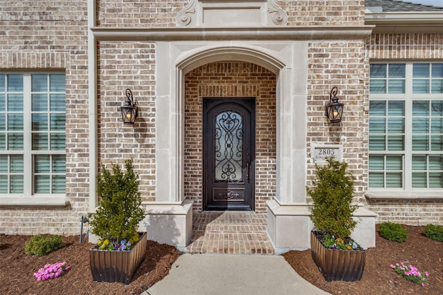 entrance to property featuring brick siding and roof with shingles