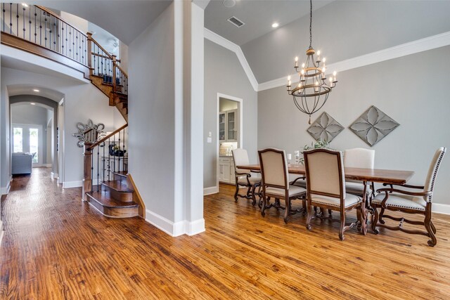 dining area featuring visible vents, wood finished floors, arched walkways, crown molding, and stairs