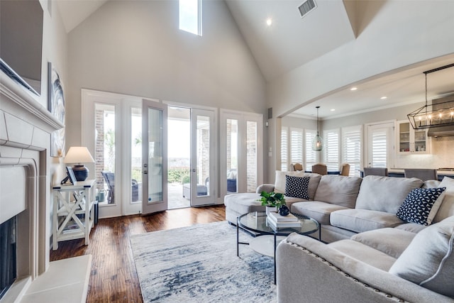 living area with visible vents, high vaulted ceiling, a notable chandelier, wood finished floors, and arched walkways