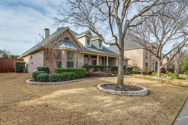 view of front of property with a front yard, fence, brick siding, and a chimney