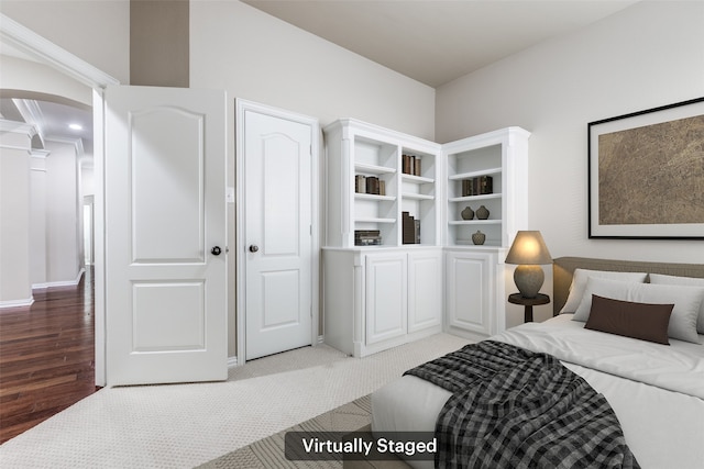 bedroom with arched walkways, light carpet, and light wood-style flooring