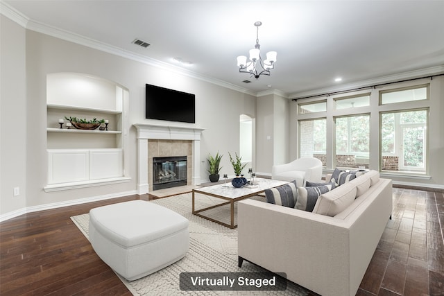 living room with visible vents, a tiled fireplace, crown molding, and hardwood / wood-style flooring