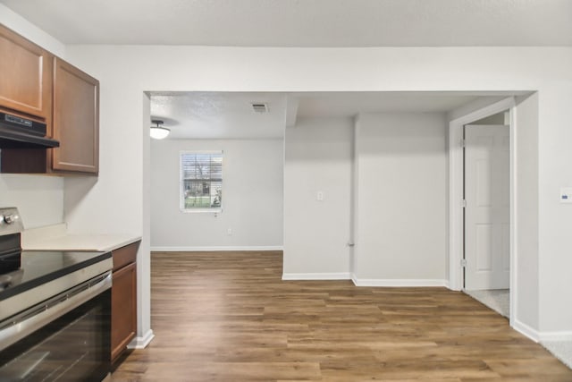 kitchen with visible vents, baseboards, under cabinet range hood, light wood-style floors, and electric range