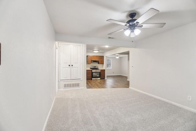 unfurnished living room featuring visible vents, light colored carpet, baseboards, and ceiling fan