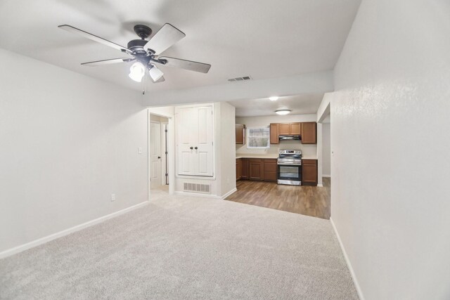 unfurnished living room with ceiling fan, baseboards, visible vents, and light carpet