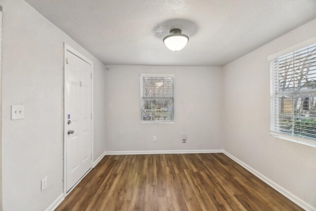 empty room with wood finished floors, baseboards, and a textured ceiling