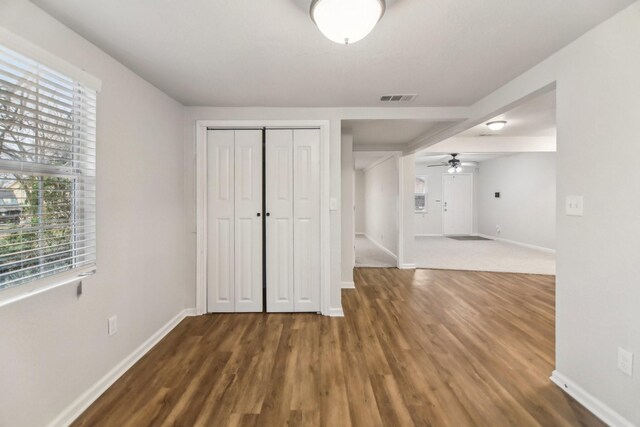 unfurnished bedroom featuring wood finished floors, visible vents, a closet, and baseboards