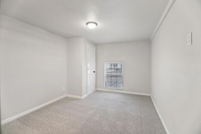 unfurnished room featuring carpet and baseboards